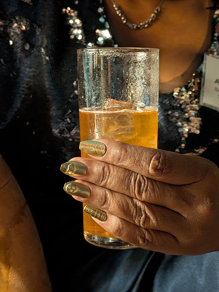 drink in hand with elegant badass nails made of brass during Holiday Nails class at the jeweler's saw jewelry studio