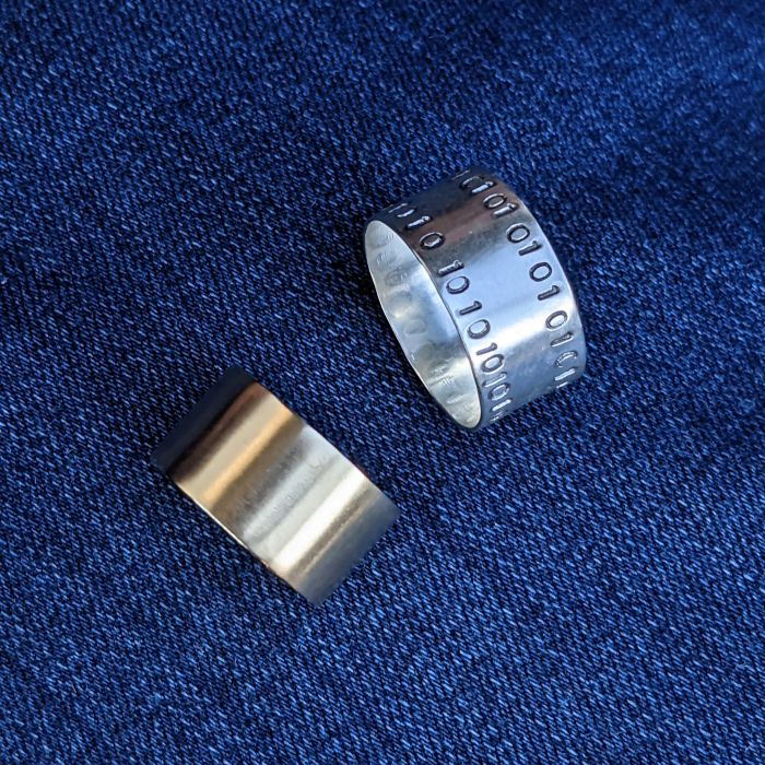 two simple wide ring bands. one with 0101 stamped on the perimeter of the band